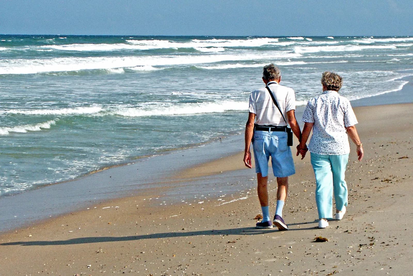 Older couple walking on the beach with clear vision